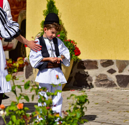 boy from Sibiu Romania meadow dressed in national linen shepherd costume, sewn with traditional black motifs, consisting of a shirt with skirt, pants, a wide leather belt, chest and wearing a black paのeditorial素材