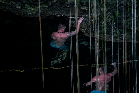 Handsome man swimming in a pool at night in the caveの写真素材