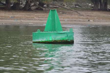 A green buoy on the shore of a lake in the spring.の写真素材