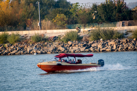 A small motorboat sails on the river in the autumn. The concept of active tourism.