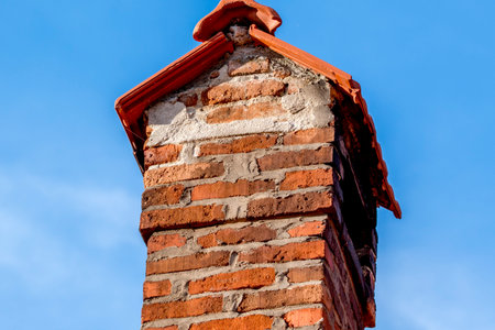 Old brick chimney against the blue sky, closeup of photoの写真素材