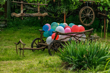 Colorful balloons in a cart on a green lawn in the gardenの写真素材