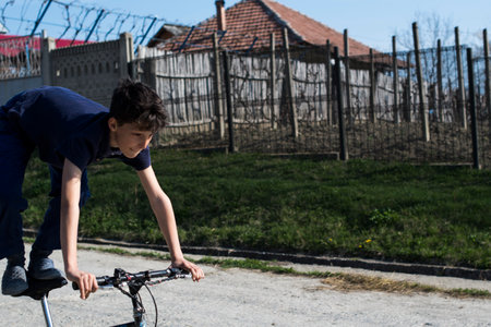 A boy in a blue T-shirt and shorts rides a bicycle on the street.