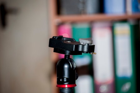 Tripod for photography on the background of bookshelves.