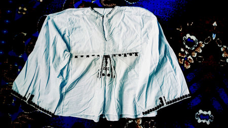 White men's shirt with embroidery on a dark background.