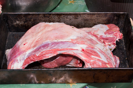 Raw pork meat in a metal tray on a green tablecloth, closeupの写真素材