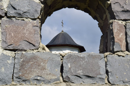 A fragment of the medieval fortress wall with a window and a cross