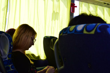 A young woman is traveling by a bus in the evening. The girl is sitting in the bus.の写真素材