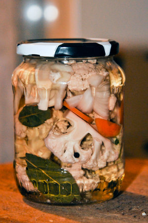 Pickled vegetables in a glass jar on a wooden table in the kitchenの写真素材