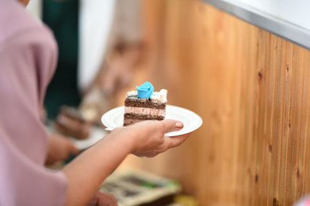 Hands of female staff holding a piece of cake in a cafeの写真素材