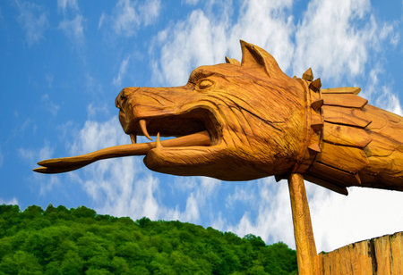 Wooden dragon statue on the background of the blue sky with cloudsの写真素材