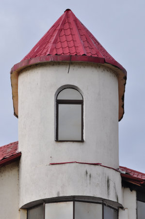 White tower with red roof and window on the background of gray skyの写真素材