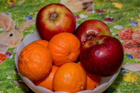 Apples and tangerines in a plate on a tablecloth