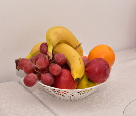 Fruit in a white bowl on a white tablecloth against the wallの写真素材