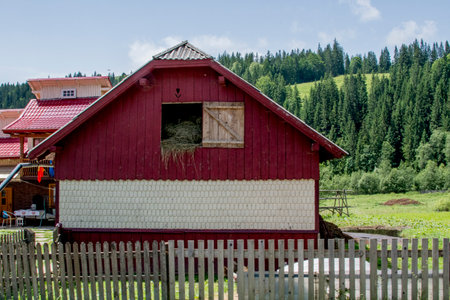 Wooden house with red roof and wooden fence.