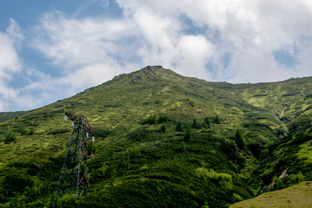 High-voltage tower on a green hillside in the mountains