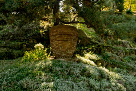 Old stone vase on the green meadow in the forest.の写真素材