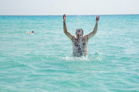 Happy young man splashing water on the beach.の写真素材