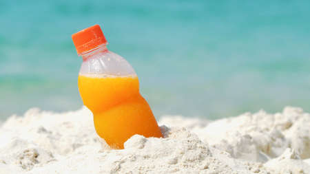 Bottle of orange juice on the beachの写真素材