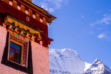 Beautiful scenery in the autumn colors with temples built in Tibetan art style in Yading National Park amid beautiful snowy mountainsの写真素材