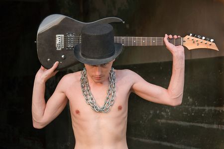 Portrait of naked boy with electric guitar in a black hat.の写真素材