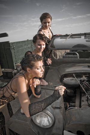 Three beautiful girls are trying to repair their car.の写真素材