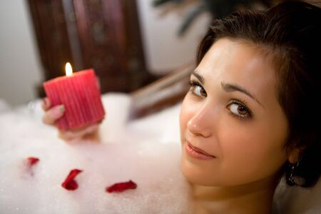 Pretty girl with candle is laying in the foam