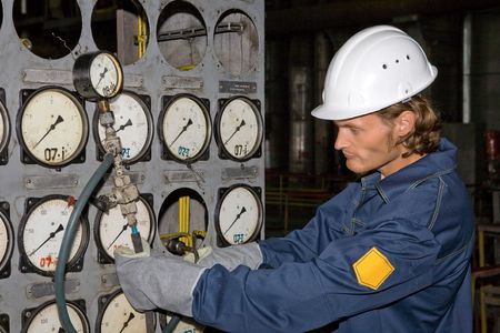 Yong worker in uniform is inspecting the pressure with a manometer