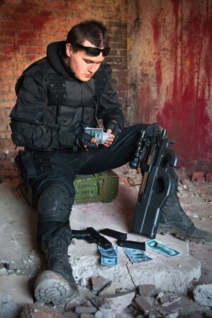 Mercenary with the rifle and money on the bloody wall backgroundの写真素材