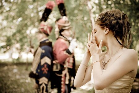 Portrait of pretty crying woman dressed in vintage dress and accessories. Duelling hussars on the...