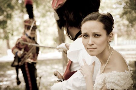 Portrait of pretty woman dressed in vintage dress and accessories. Duelling hussars on the background.の写真素材