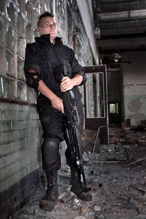 Warrior with the machine gun on the ruined building background.の写真素材