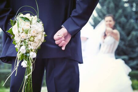 Bridal game. Groom is holding bridal rings in the one hand and bride's bouquet in the other. Bride...