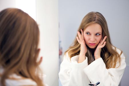 Pretty girl in the bathrobe is going to make a make-up near the mirrorの写真素材