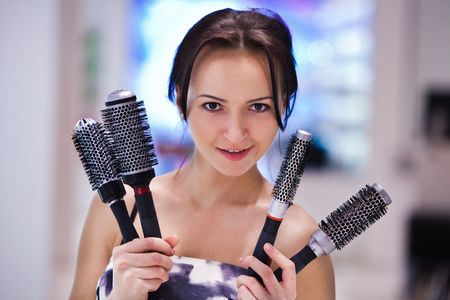 Pretty girl with the hair brushes. Blurred colorful background.の写真素材