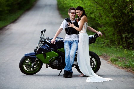 Beautiful smiling couple near powerfull sport motorbike. Forest road on the background.の写真素材