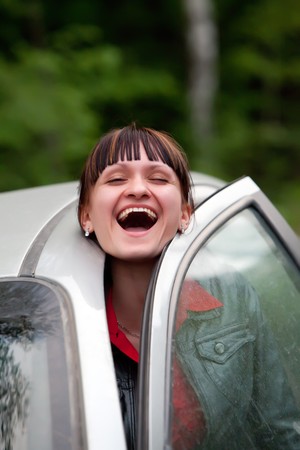 Pretty girl is laughing trapped with the car door.の写真素材