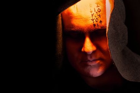 Mystery monk with the runes on the face. Portrait in the shadows.