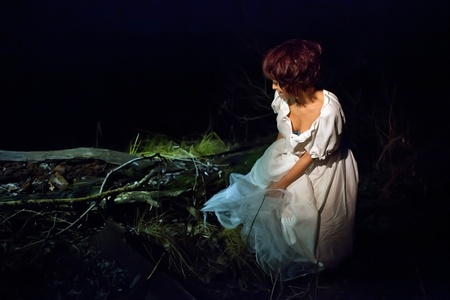 Girl in vintage white dress lost in the dark forest.の写真素材