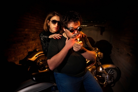 Pretty couple is sitting on the motorcycle. Brick wall on the background.の写真素材