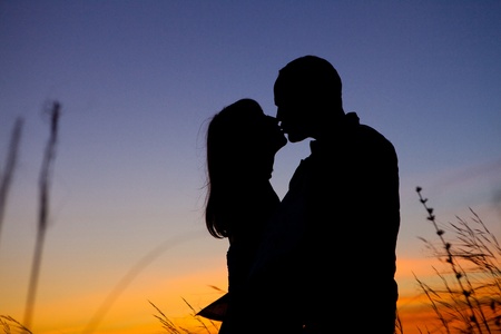 Pretty couple in the meadow on the sunset background.の写真素材