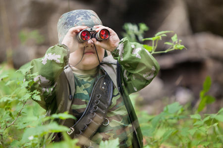 Yong hunter with the spyglass is posing on the forest  の写真素材