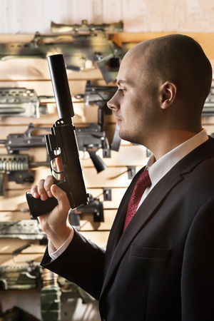 Bald hitman with the gun on the armory wall background.の写真素材