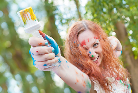 Laughing woman with the paintbrush is ready for creative battleの写真素材