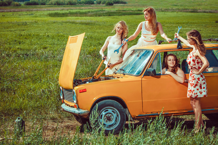 Beautiful women with tools are repairing a car on the rural roadの写真素材