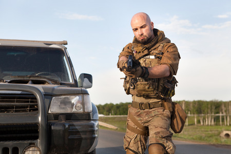 Aiming soldier in american uniform. Military SUV on the background.