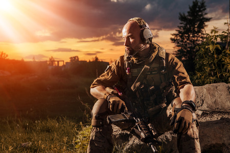 American soldier with the M4 rifle is having a rest. Sunset on the background.の写真素材