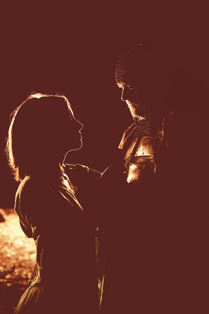 Silhouettes of medieval knight in heavy armor and his princess. Artistic toning.の写真素材