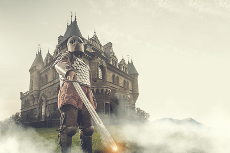 Medieval knight with the sword on the ancient castle background. Low contrast post processing.の写真素材