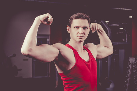 Powerful man with muscular build is posing in the gym. Artistic toning.の写真素材